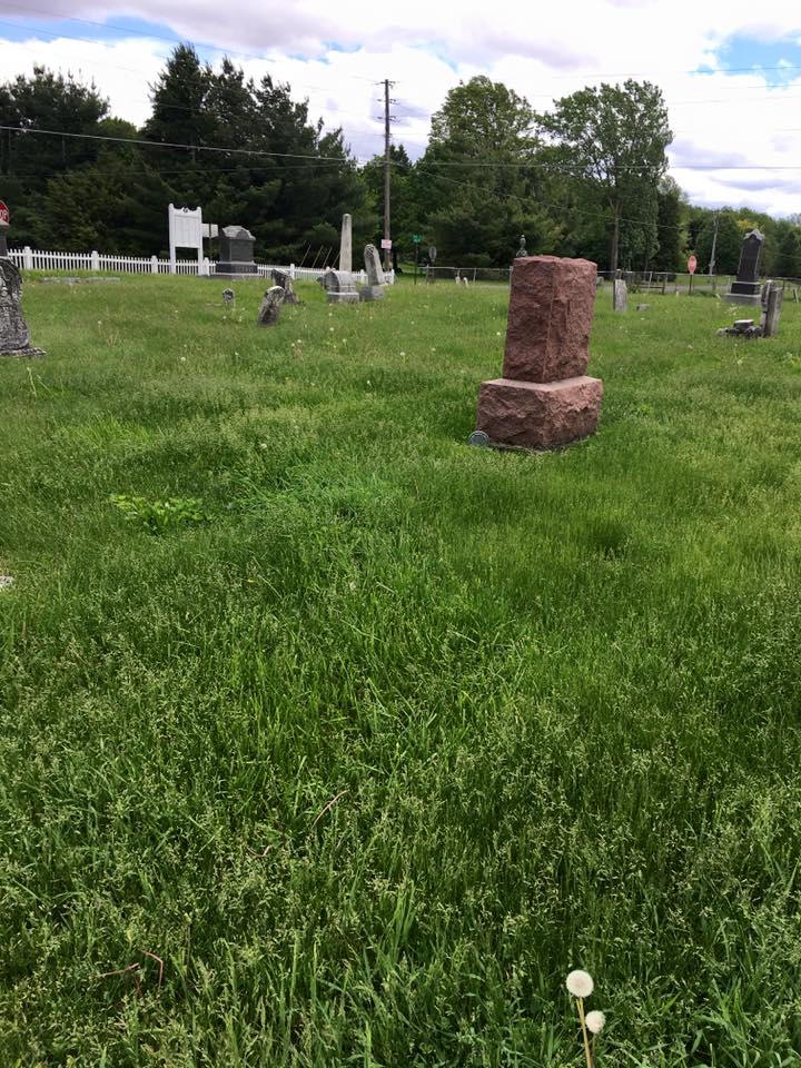 Cemetery headstones with red sandstone monument